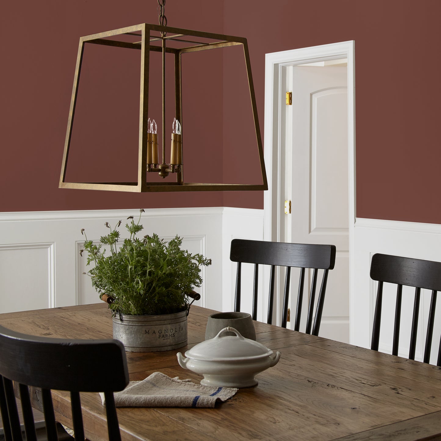 Mountain Currant paint featured in dining room walls with large brass pendant light and wooden dining table