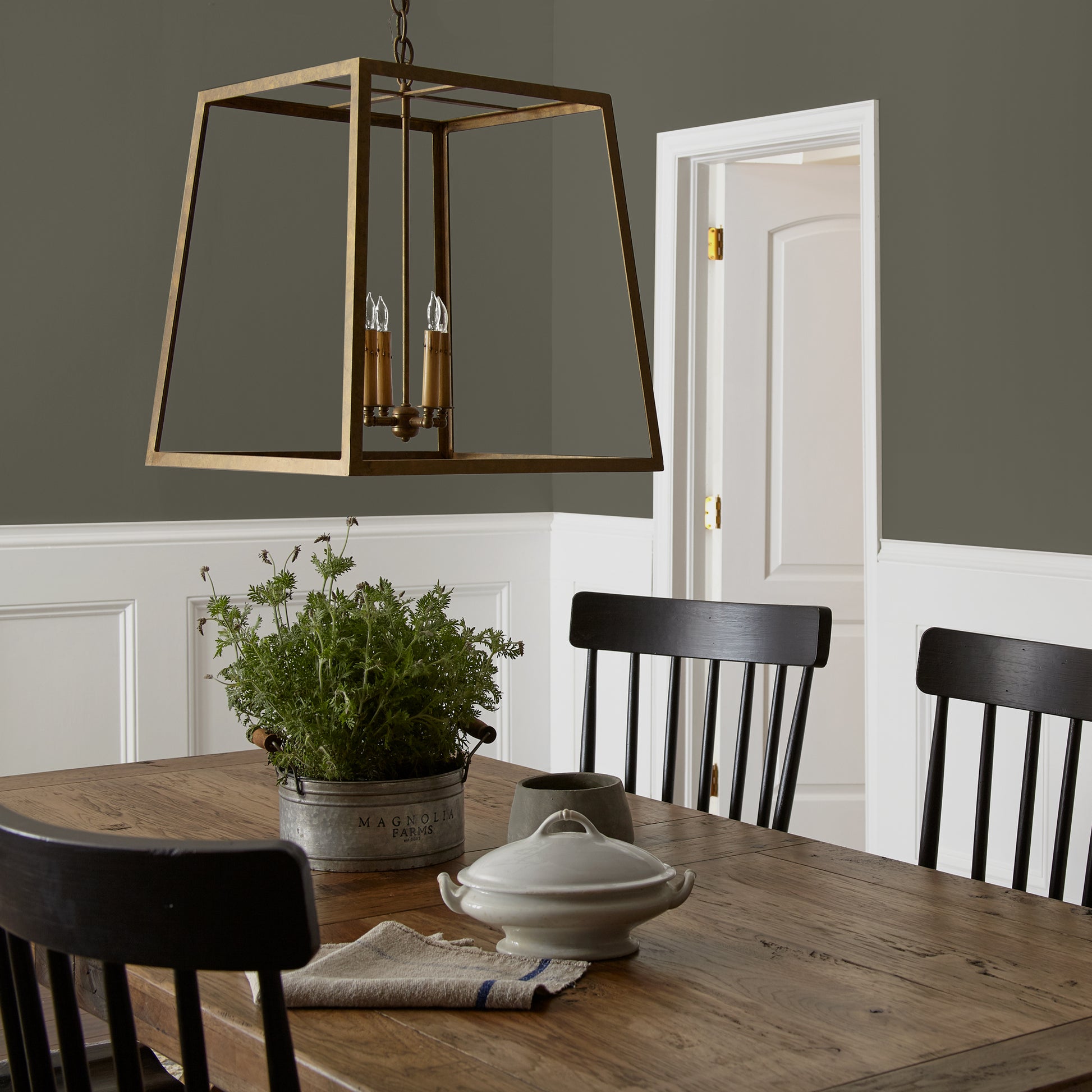 Trailhead paint featured in dining room walls with large brass pendant light and wooden dining table