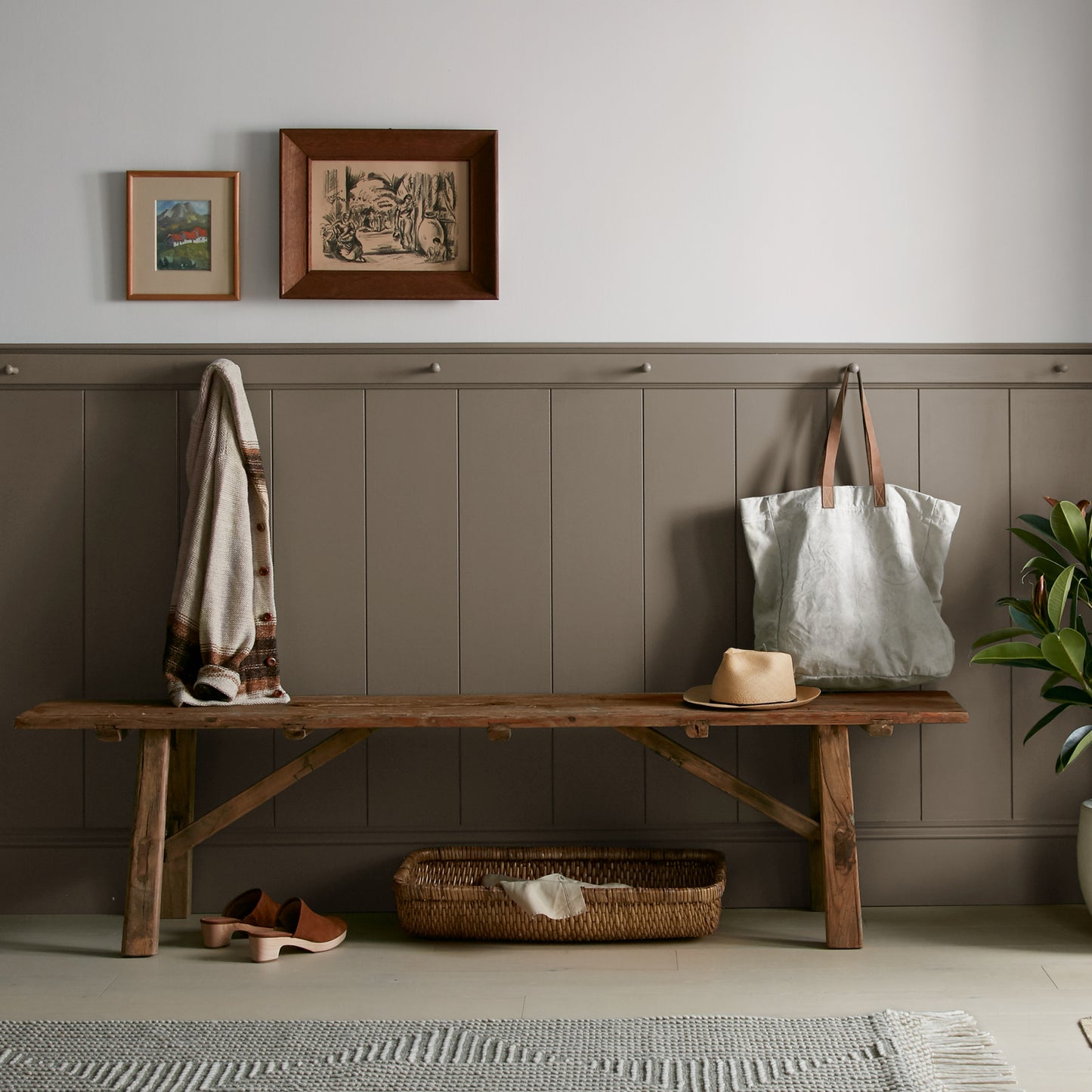 Mosswood paint featured in mudroom on half room paneled walls with hung tote bag and cardigan