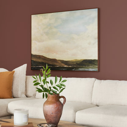 Mountain Currant paint featured in living room walls with large landscape picture above cream sectional and brown vase and greenery