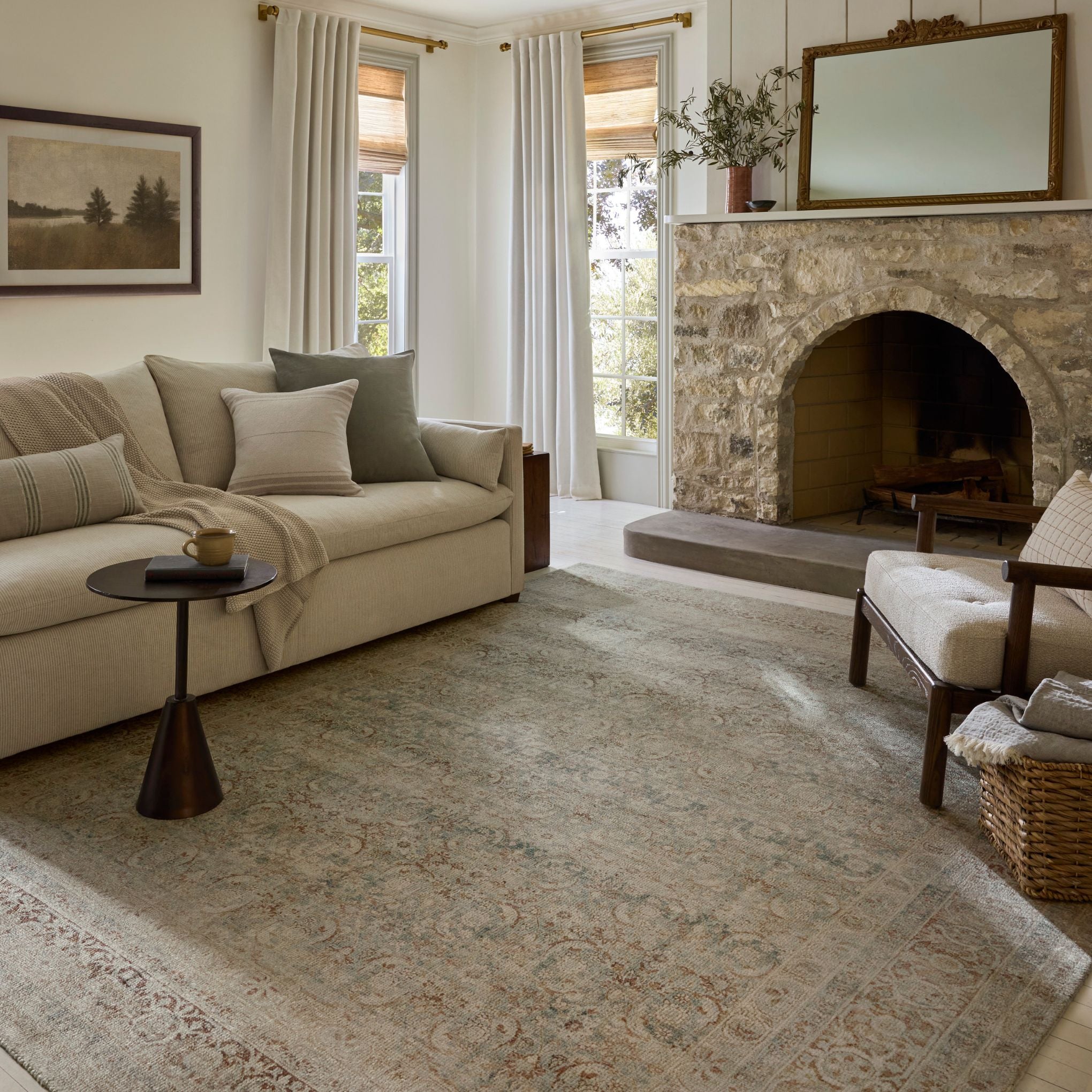 Living room with beige sofa, stone fireplace, and large mirror.