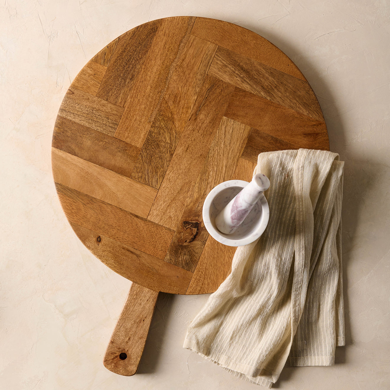 Wooden cutting board with a white bowl and cloth on a beige surface