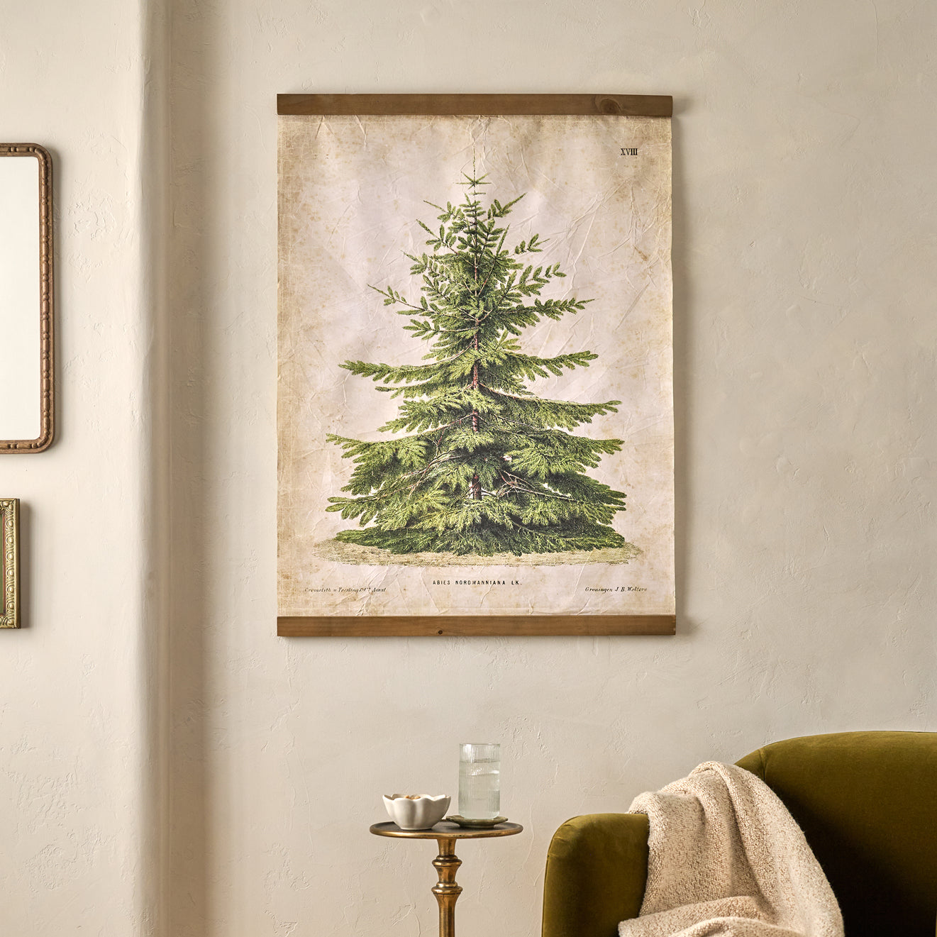 Wall tapestry of a green tree on a beige wall above a green armchair and side table.
