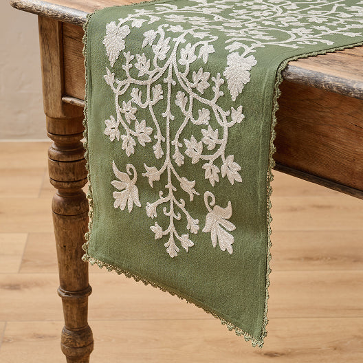 Green embroidered table runner on a wooden table