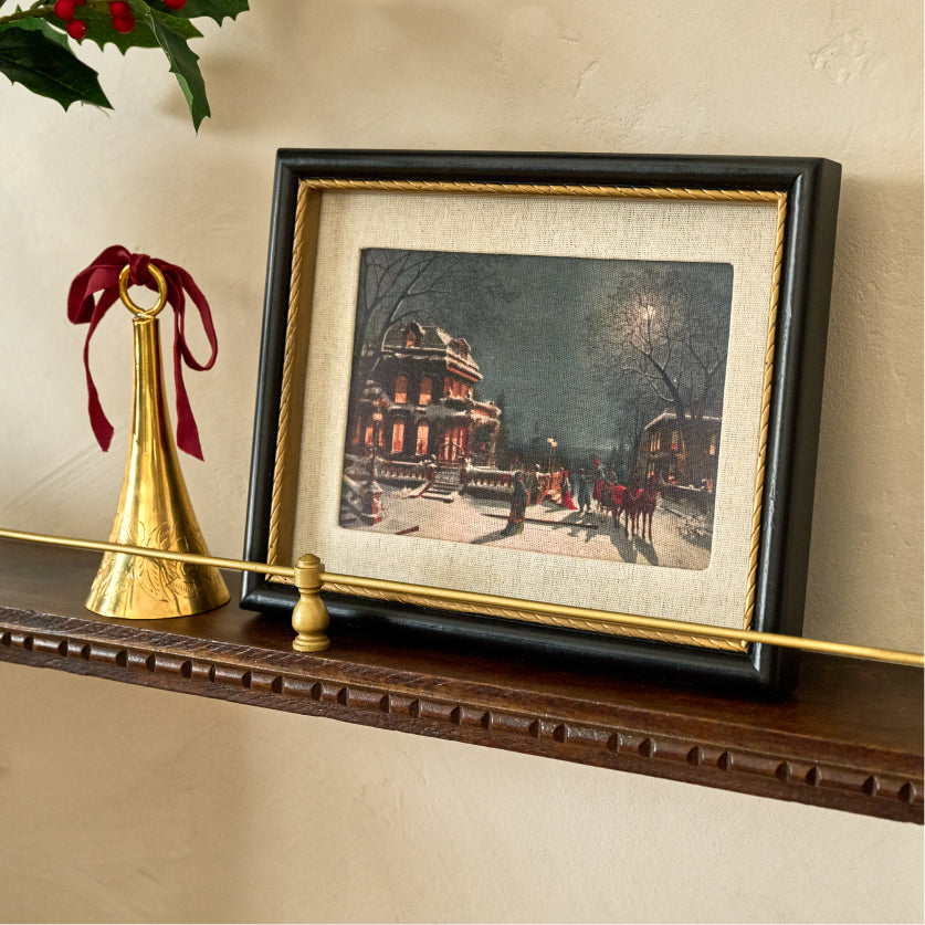 Framed artwork on a wooden shelf with decorative elements