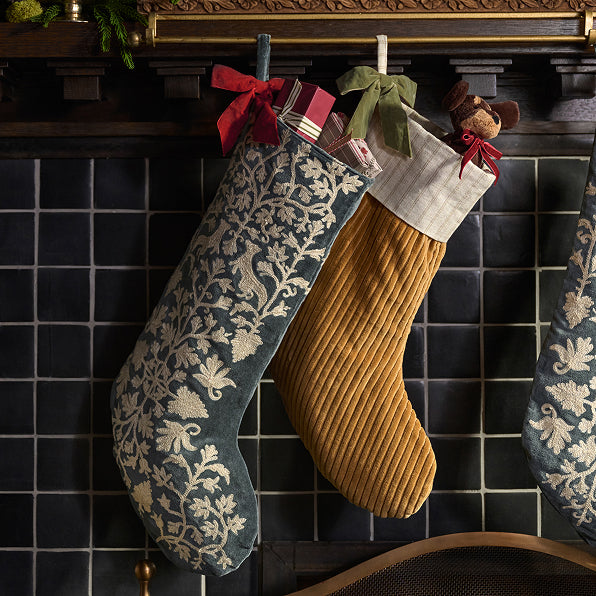 Two Christmas stockings hanging on a fireplace with decorative ribbons.