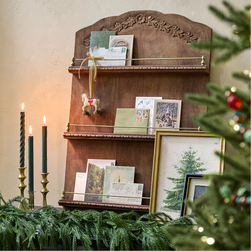 Wooden shelf with decorative items on a mantel against a neutral wall.