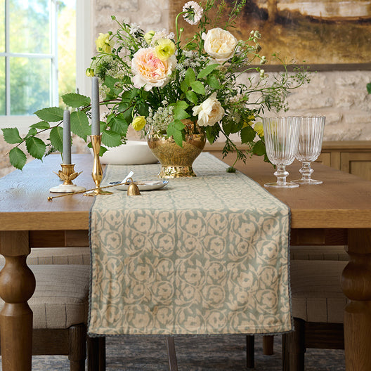 Dining table set with floral centerpiece, candles, and patterned table runner.