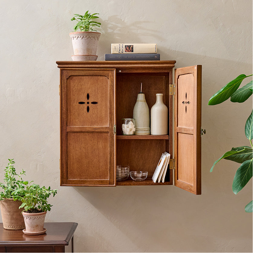 Wooden wall-mounted cabinet with open doors displaying decorative items against a beige wall.
