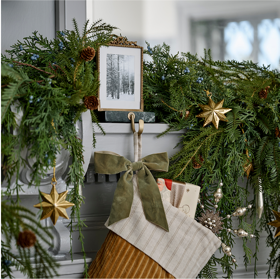 Decorative Christmas mantel with greenery, stockings, and ornaments.
