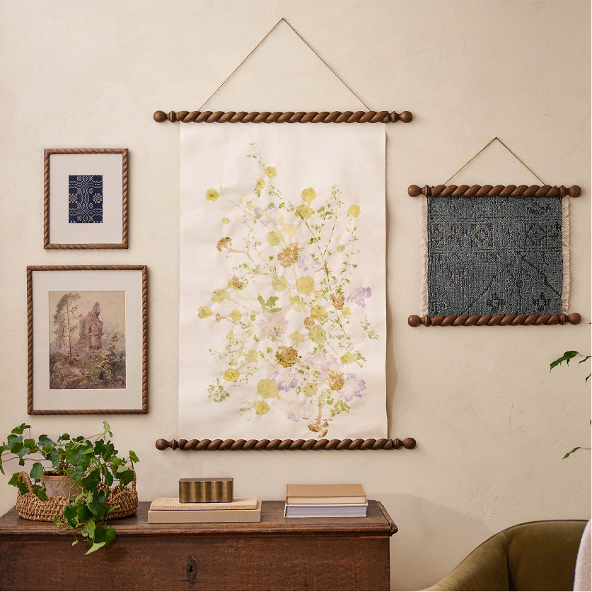 Decorative wall art pieces on a neutral wall with a wooden shelf below.