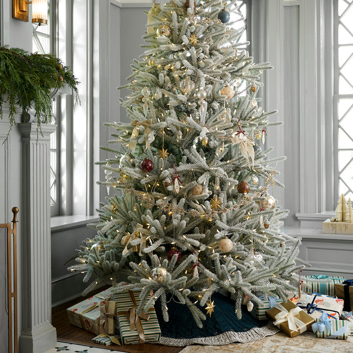 Decorated Christmas tree with ornaments and presents in a room with a fireplace.