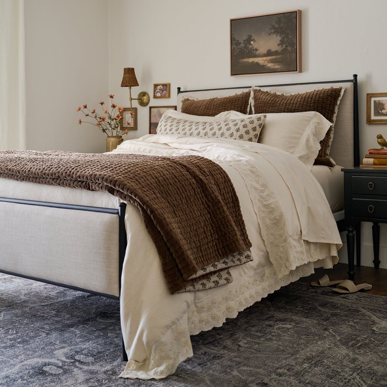 Neatly made bed with brown and white bedding in a bedroom setting.