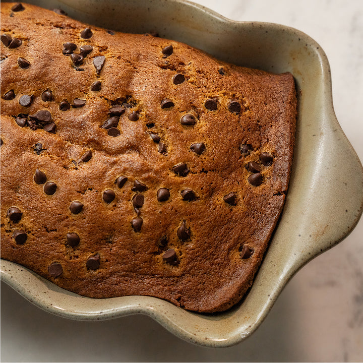 Chocolate chip cake in a ceramic dish on a marble surface