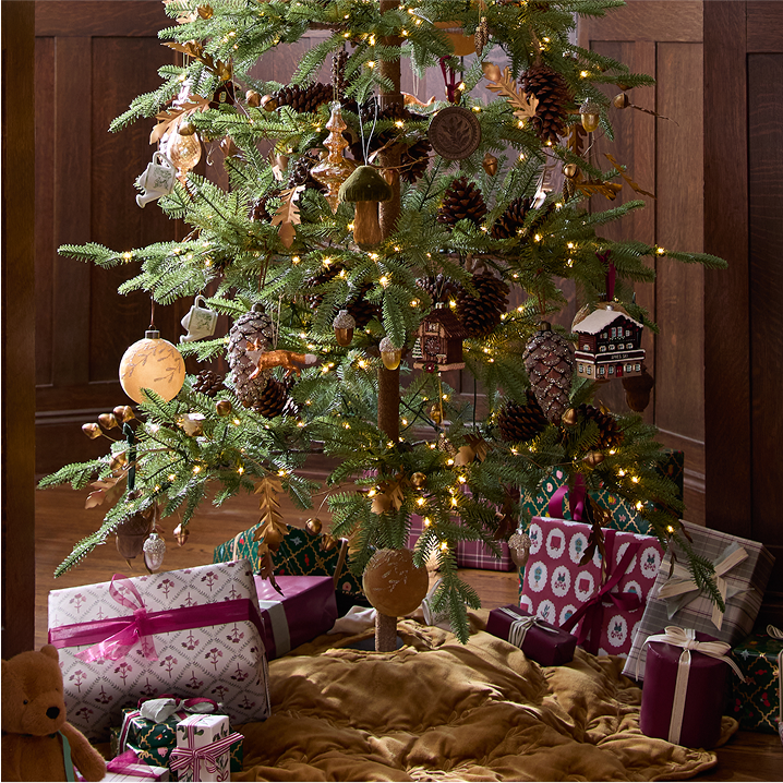 Decorated Christmas tree with lights and ornaments, surrounded by wrapped gifts on a wooden floor.