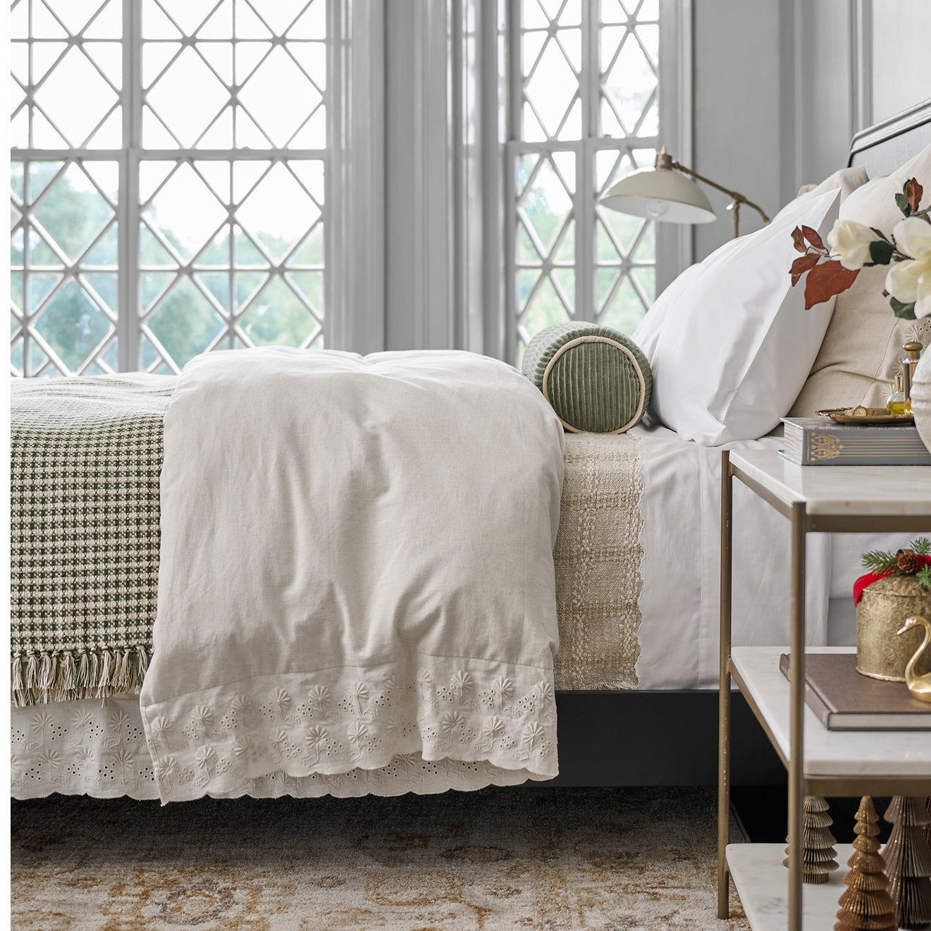 Neatly made bed with white bedding and decorative pillows in a bedroom setting.