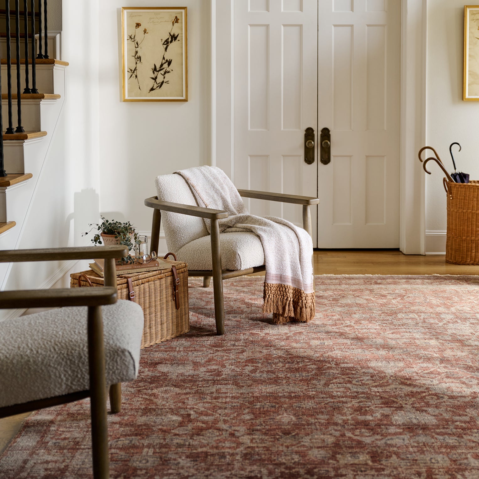 Living Room with two neutral accent chairs.  One chair has a throw blanket draped over the back.  There is a red floral rug laying across the entire floor.