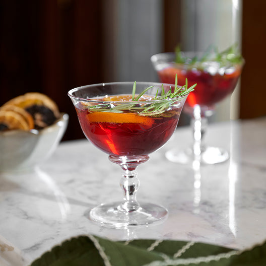 Two cocktails with garnishes on a marble surface