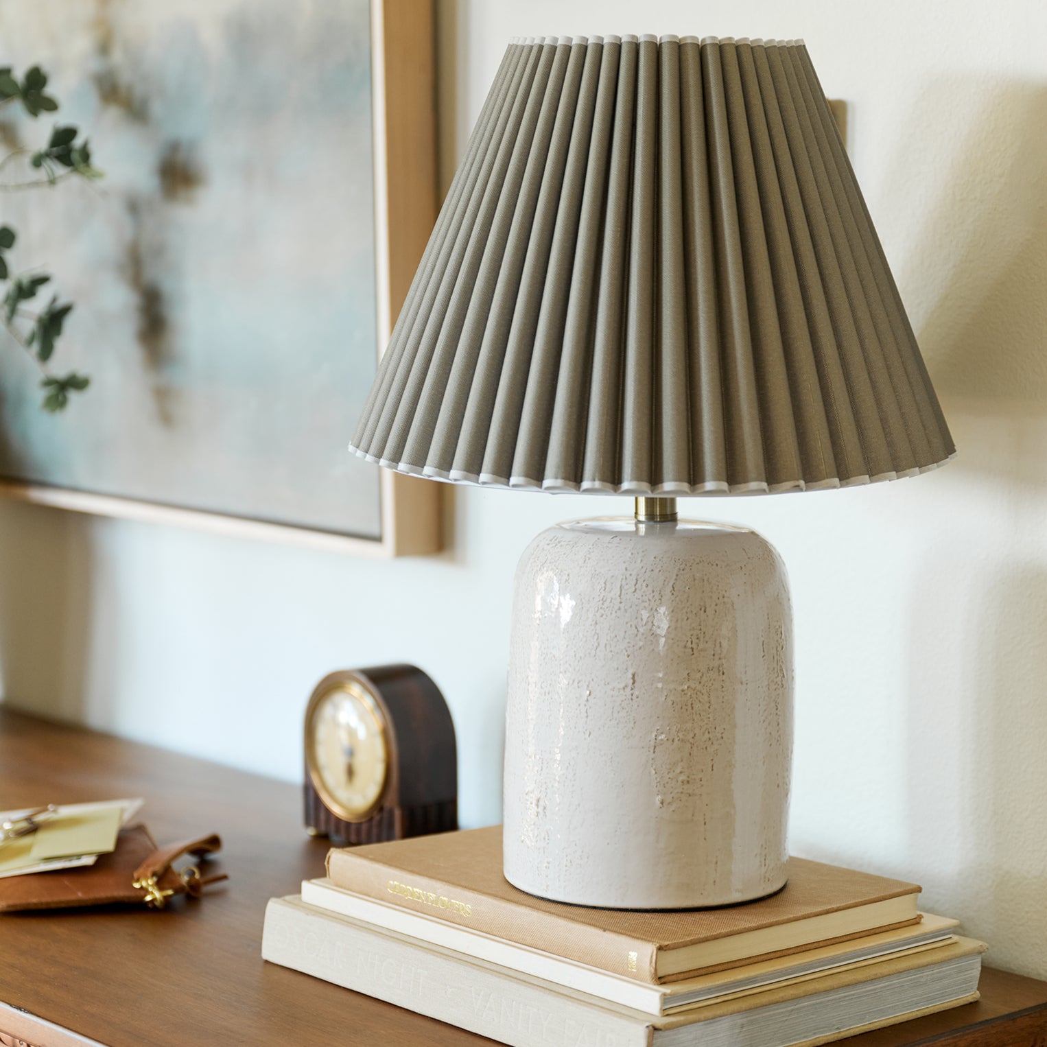 Table lamp with pleated shade on a stack of books in a home setting