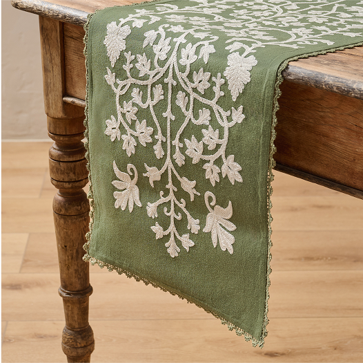 Green embroidered table runner on a wooden bench