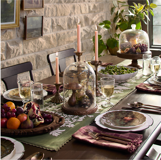 Elegant dining table setting with candles, fruits, and decorative items.