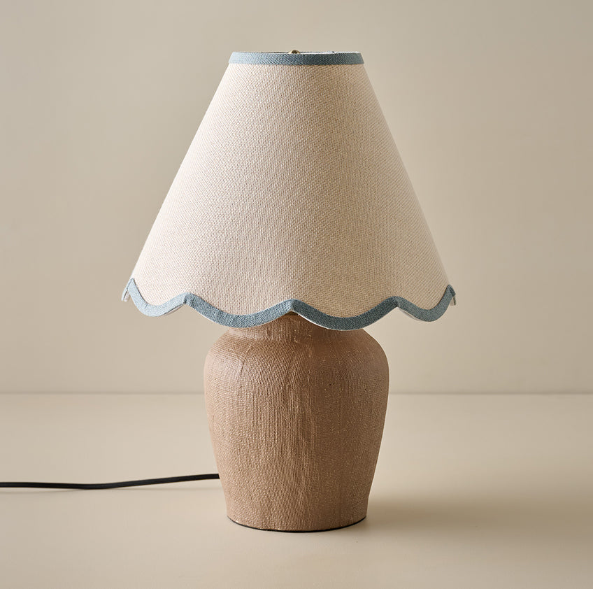 Table lamp with a beige fabric shade and wooden base on a beige background