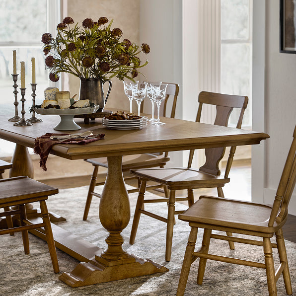 Dining room with wooden table and chairs, decorated with flowers and glasses.