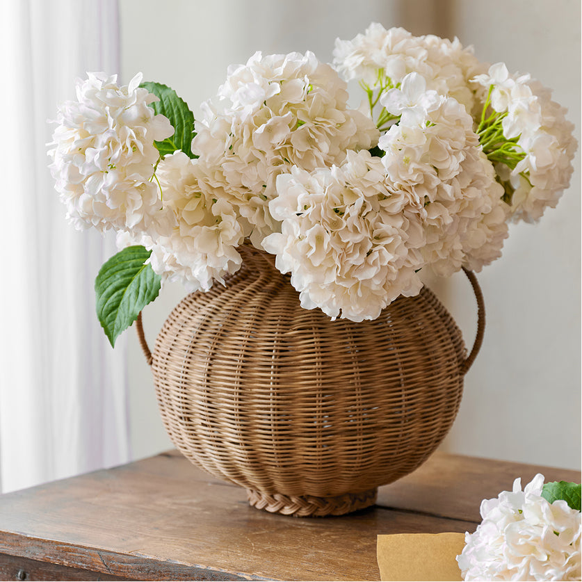 Wicker vase with white flowers on a wooden surface