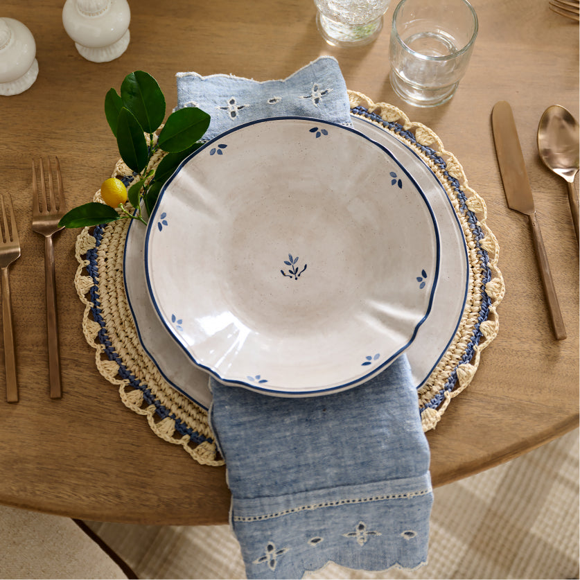 Dinner setting with decorative plates, napkin, and cutlery on a wooden table.