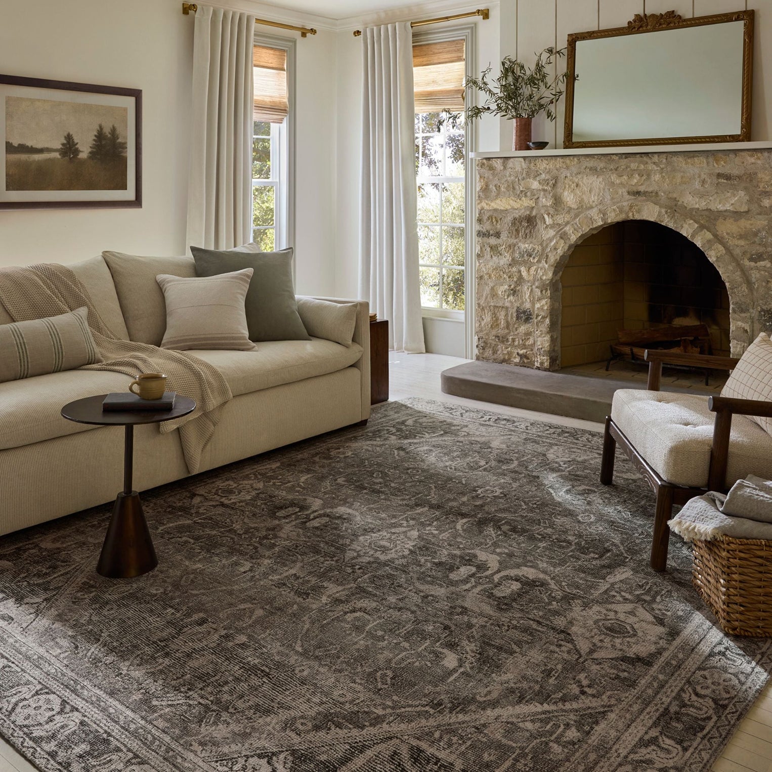 Living room with beige sofa, stone fireplace, and patterned rug.