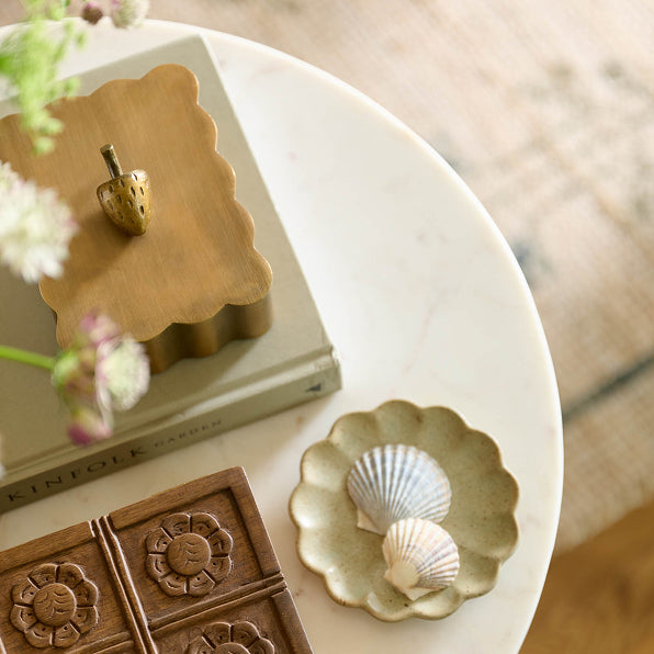 Decorative items including a wooden box, shell dish, and books on a white surface.