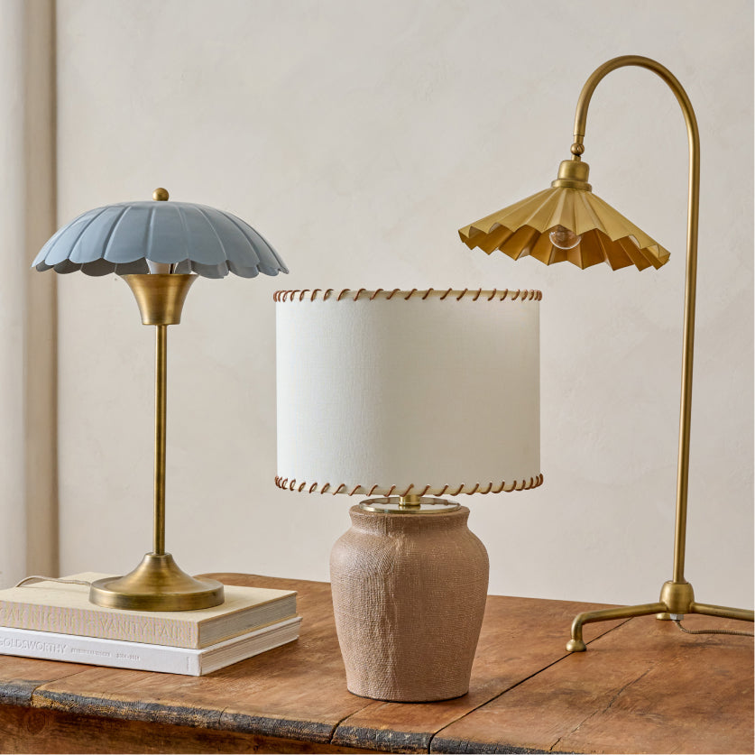 Three table lamps with different designs on a wooden surface.