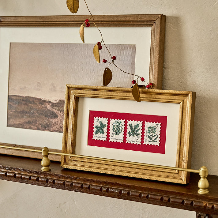 Framed artwork with decorative stamps on a wooden shelf