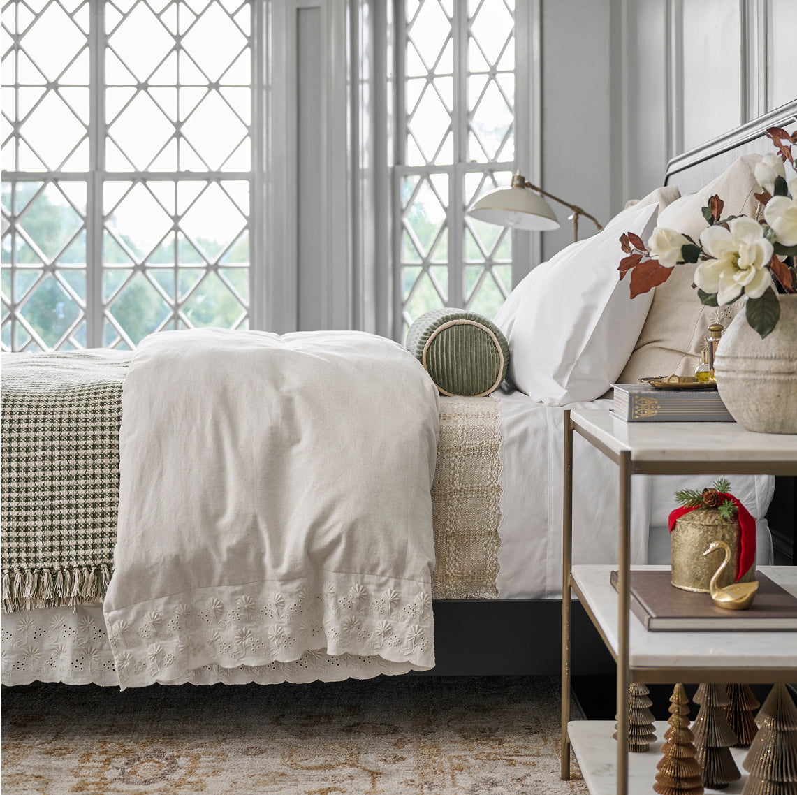 Neatly made bed with white bedding and decorative pillows in a bedroom setting.