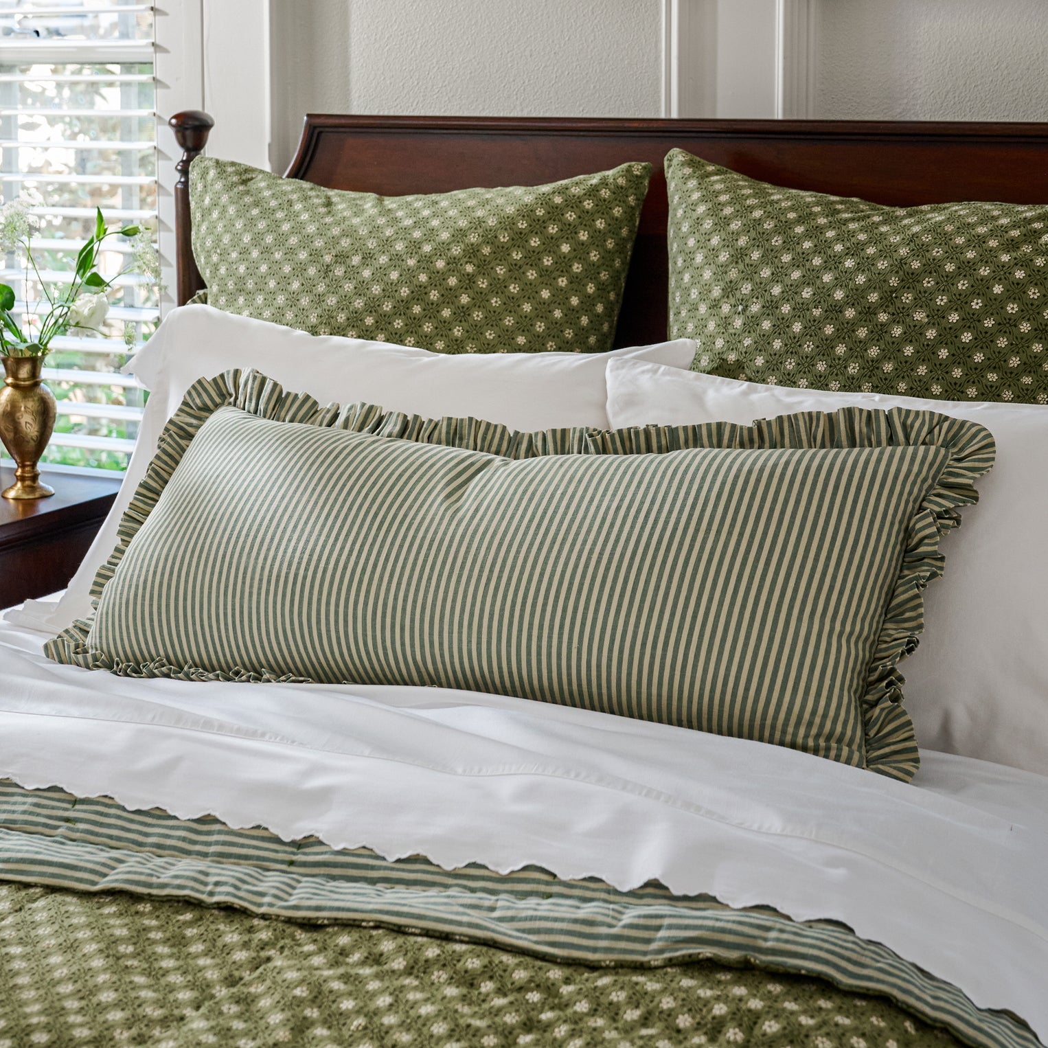 Bed with green and white patterned pillows and bedding.