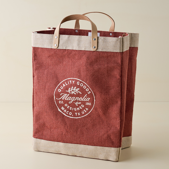 Red tote bag with 'Magnolia' logo on a beige background