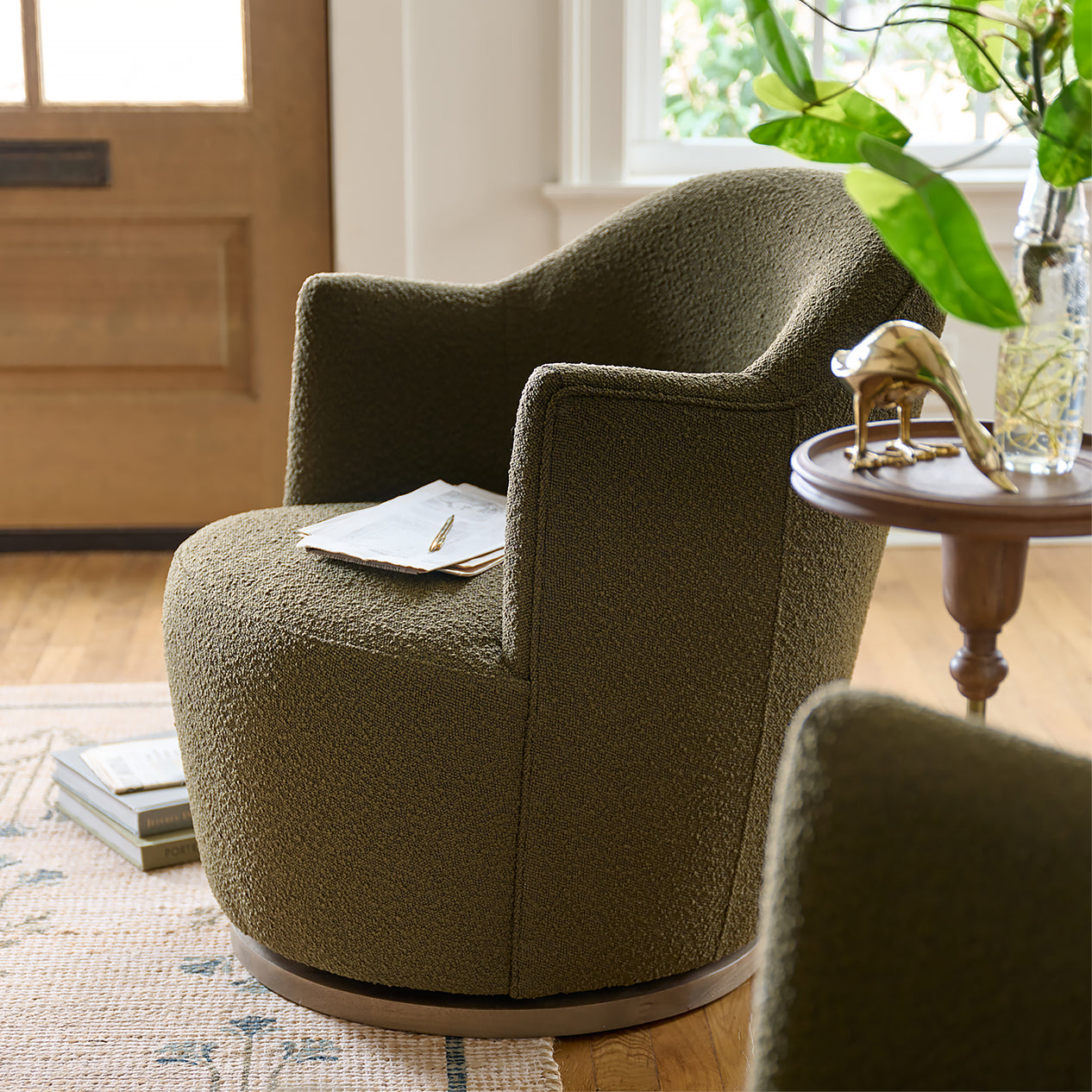 Green textured armchair in a living room setting with a side table and plant.