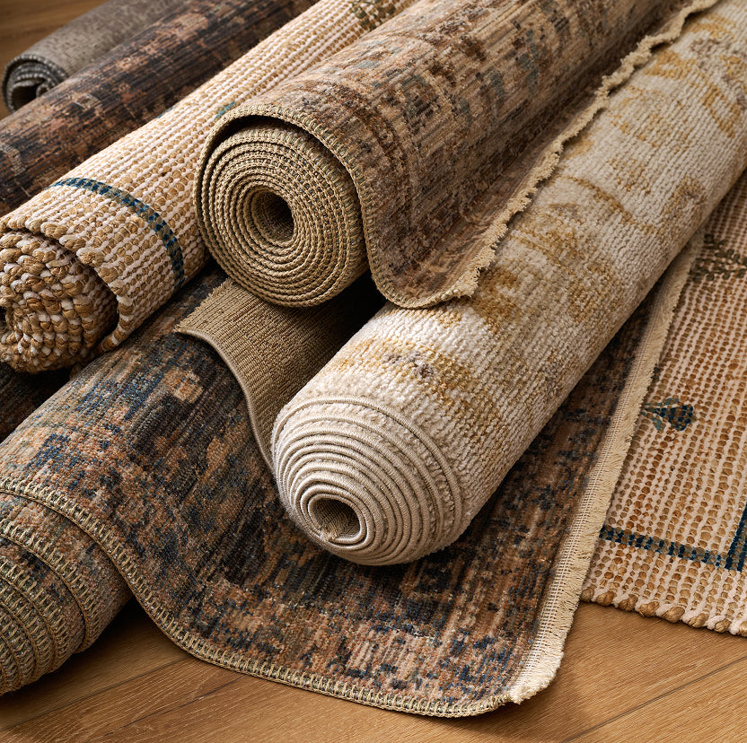 Rolls of textured rugs on a wooden floor.
