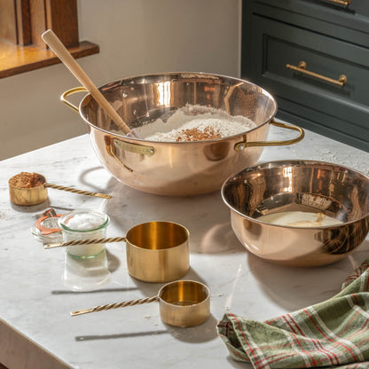 Antique Brass Twisted Measuring Cups on a counter in a baking scene