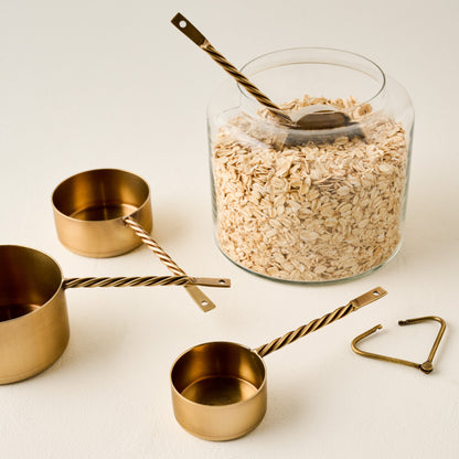 Antique Brass Twisted Measuring Cups shown with canister of oats