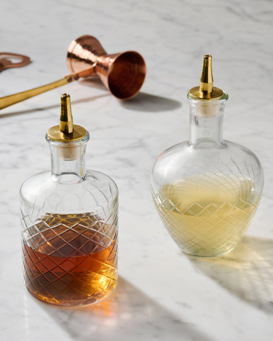 Vintage-Inspired Etched Glass Bottles shown with other bar tools nearby