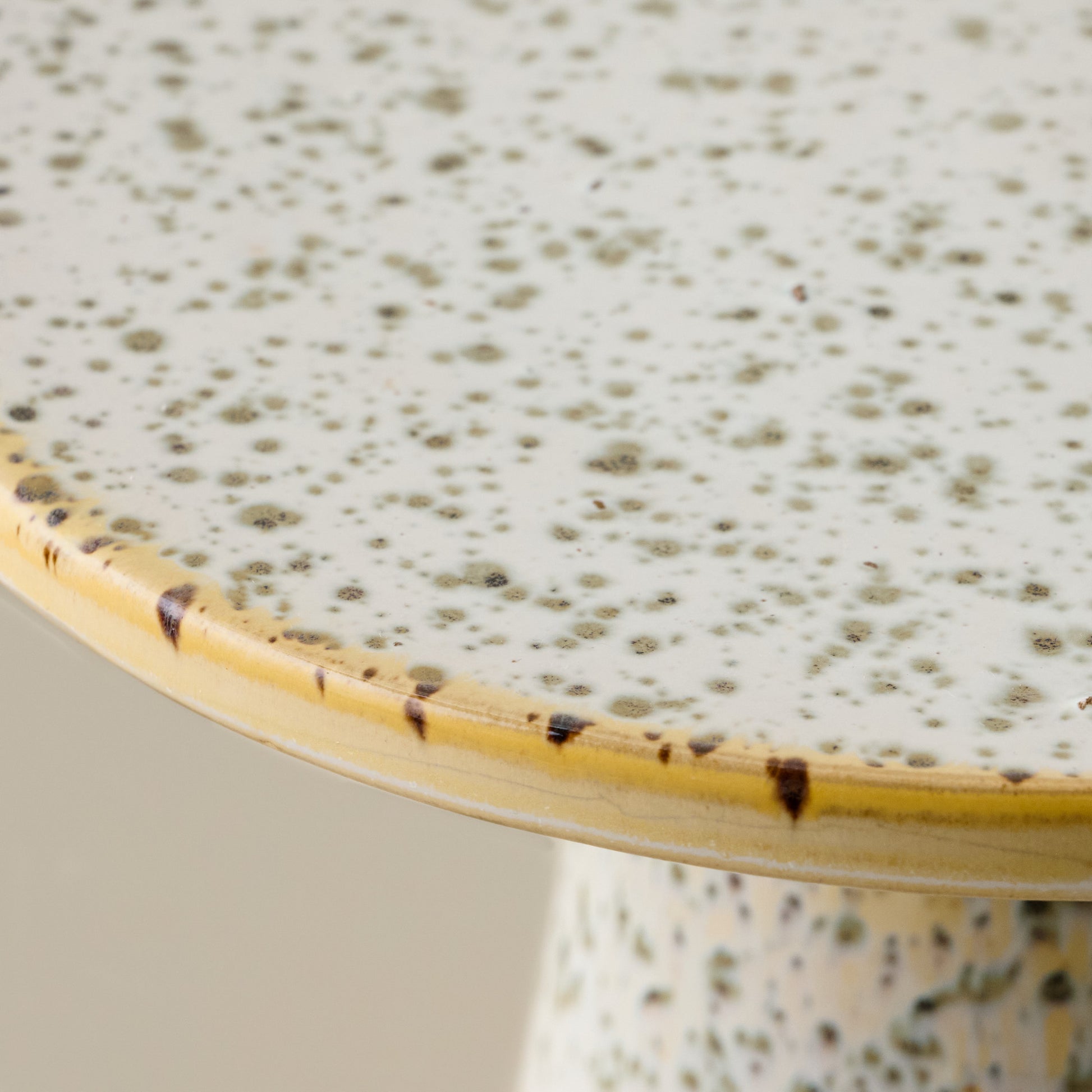 Close-up of a ceramic cake stand with speckled green glaze