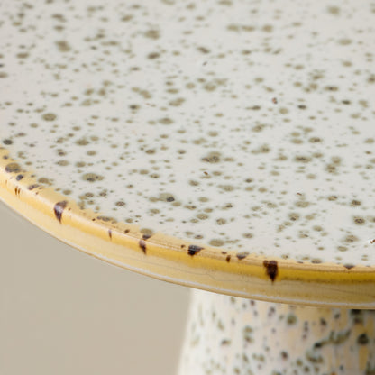 Close-up of a ceramic cake stand with speckled green glaze