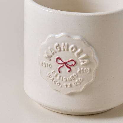 White ceramic mug with 'Magnolia' branding on a light gray background
