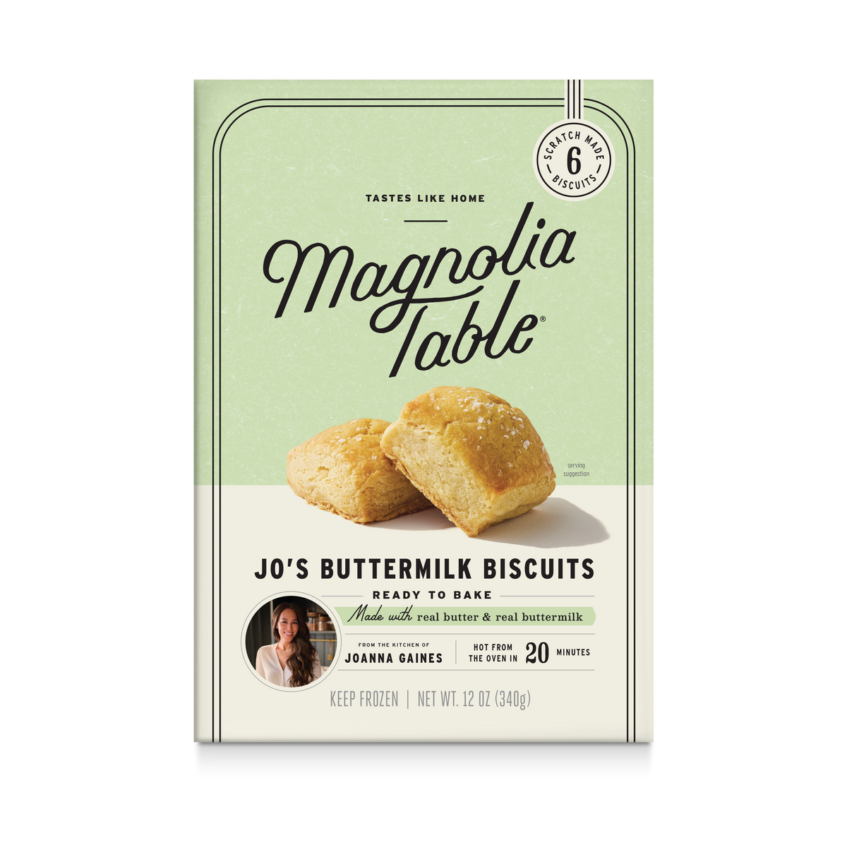 Front-facing package of Magnolia Table Jo's Buttermilk Biscuits on a plain white background. The box is light sage green on the upper half and cream on the lower half, with a photo of two golden biscuits and text including 'Tastes Like Home' and 'Ready to Bake.