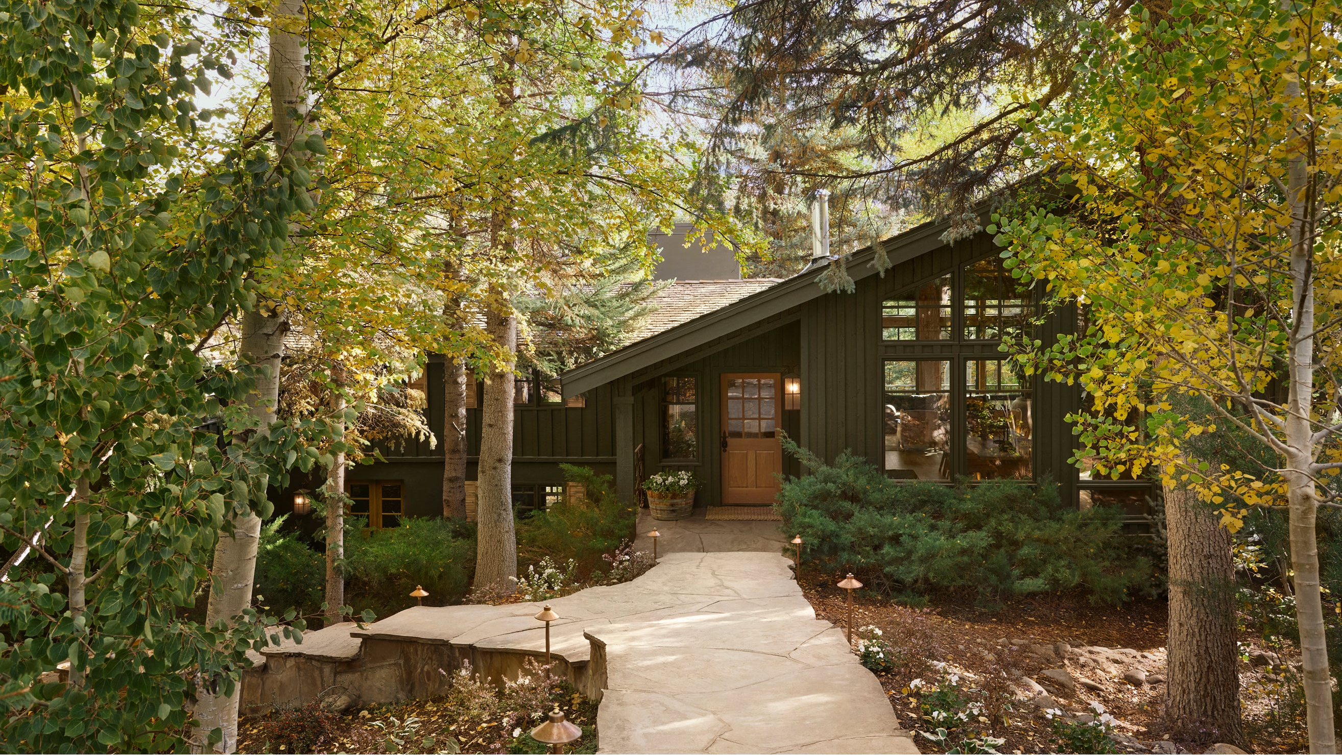 Cabin surrounded by trees with a stone pathway leading up to it.