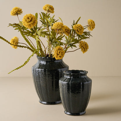 Yellow Large Thistle Bush shown in black vase with empty smaller vase nearby