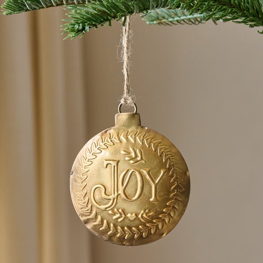 Pressed Metal Joy Ornament shown hung from tree