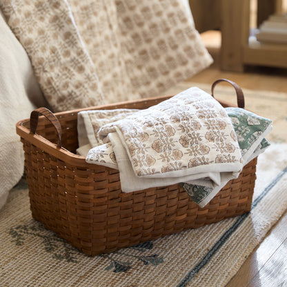 Antique Inspired Woven Harvest Basket with bedding covers in a bedroom