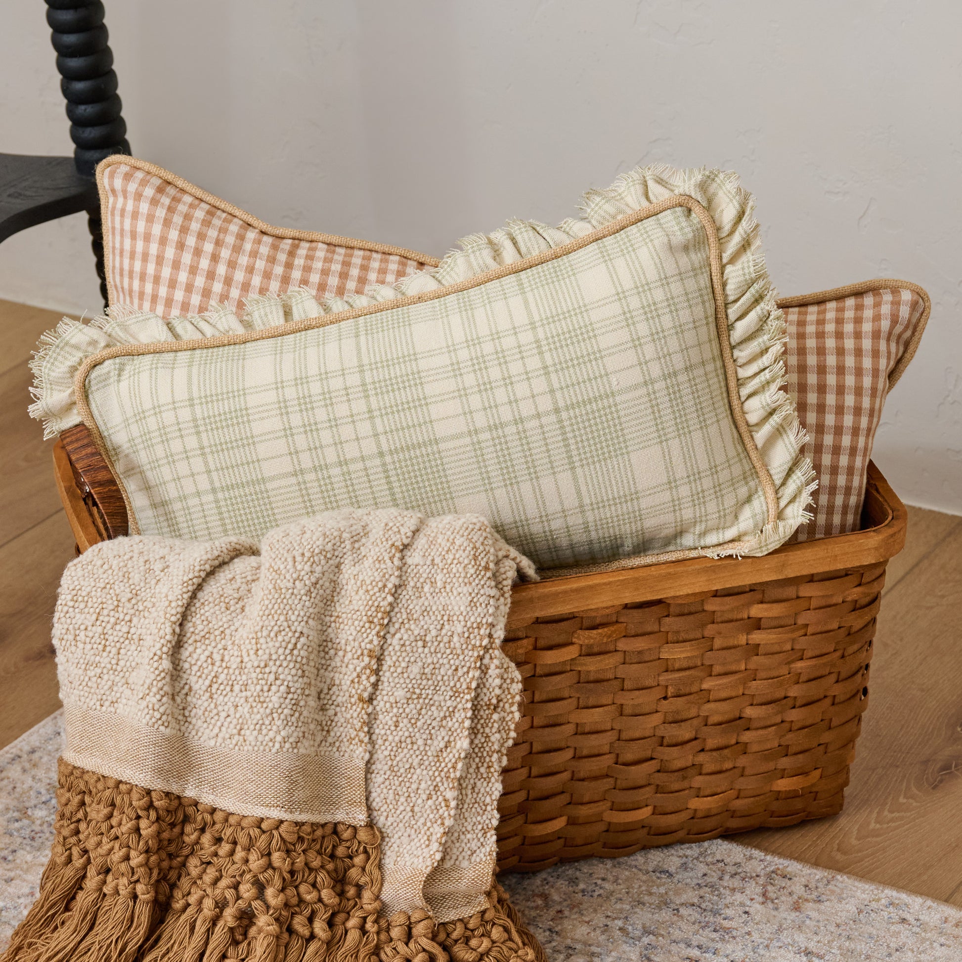 Antique Inspired Woven Harvest Basket filled with plaid pillows and throw blanket